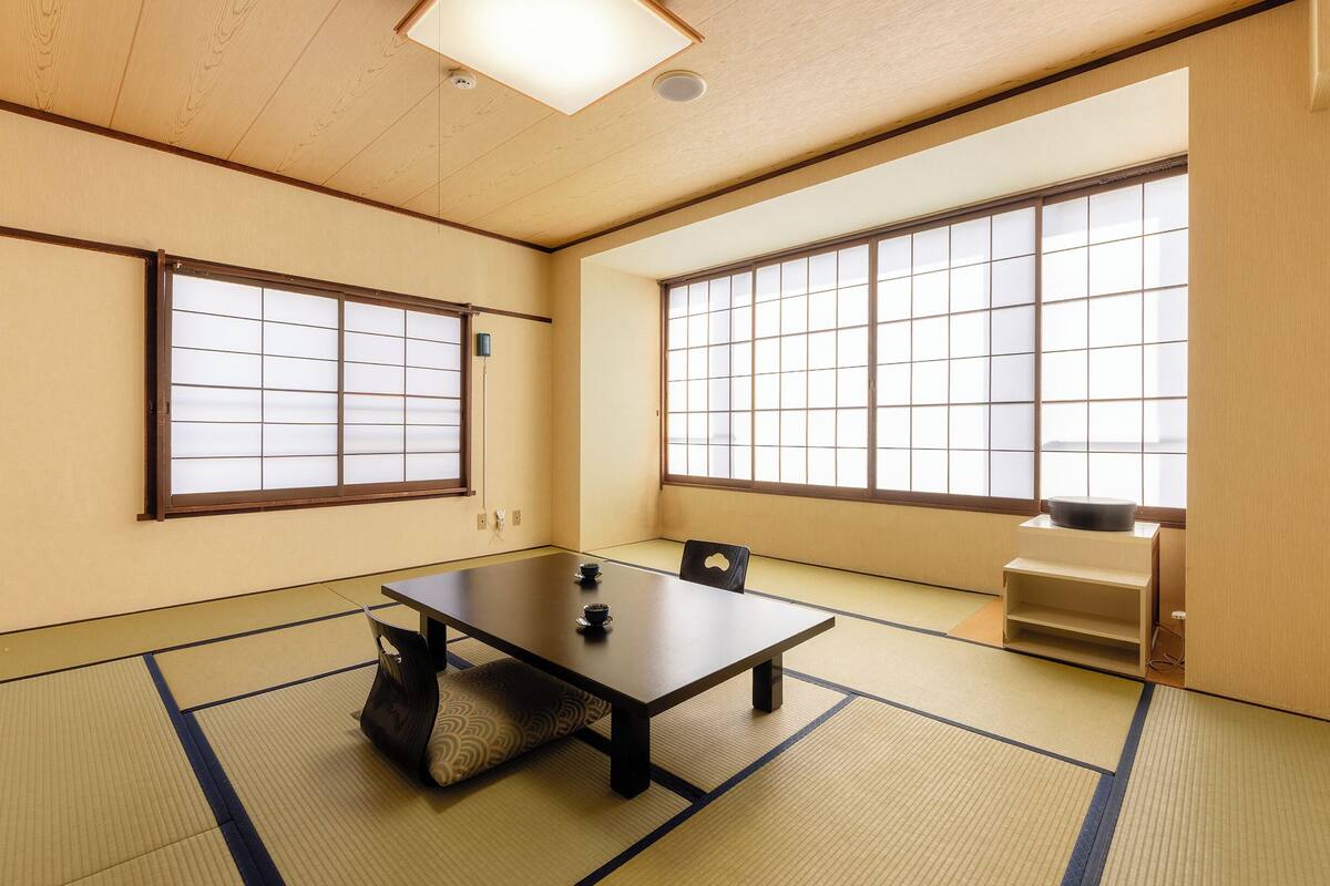 Une pièce de style japonais traditionnel, avec un sol recouvert de tatamis, une table basse et des portes coulissantes en papier de riz (shoji).