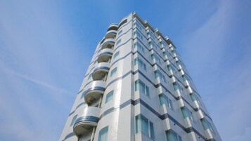Un edificio alto y moderno con una fachada curva distintiva y varios balcones.
