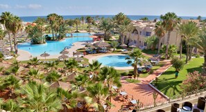 Un complexe hôtelier doté de plusieurs piscines, de palmiers et d’espaces de détente.
