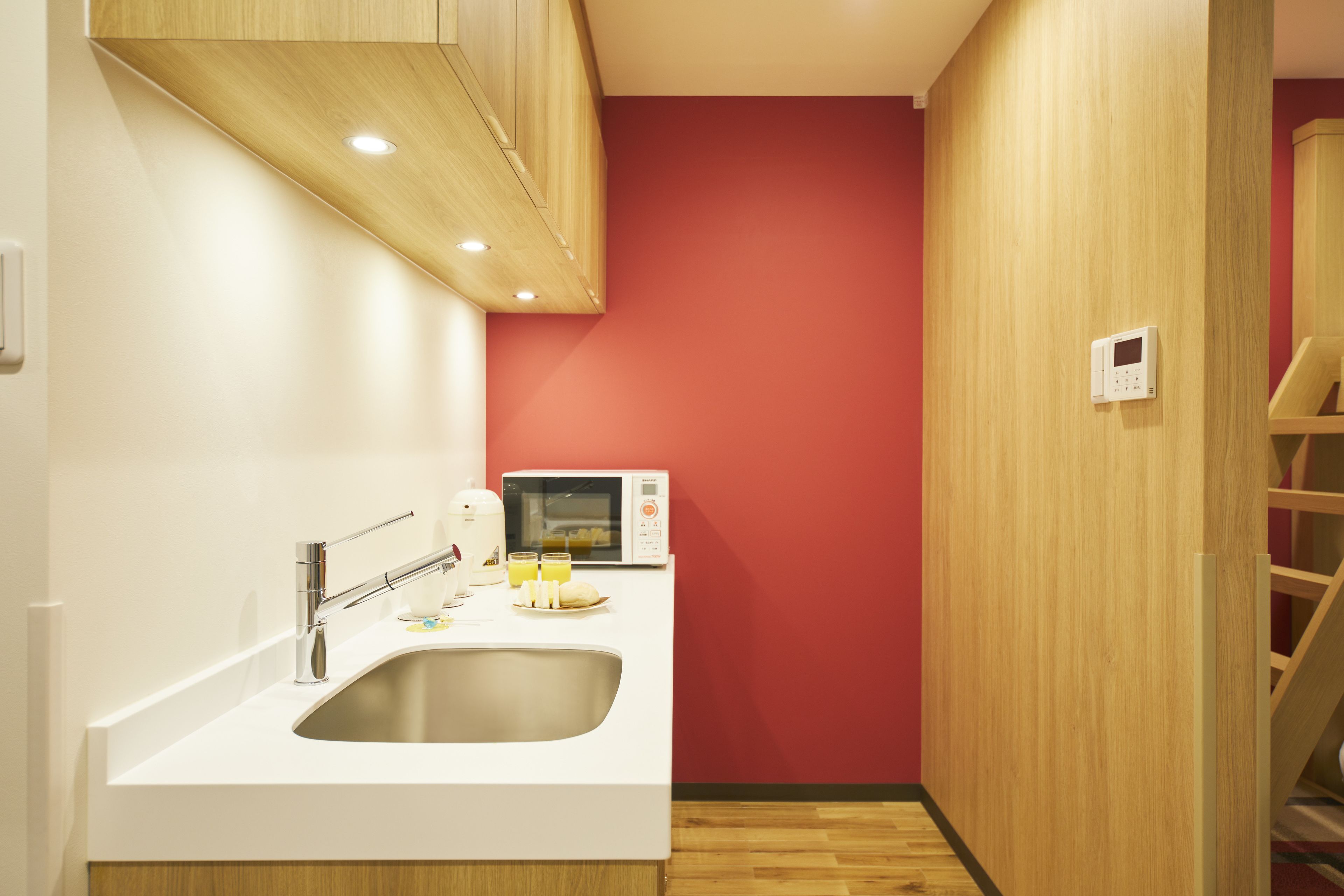 A compact kitchen with a white countertop, stainless steel sink, and a microwave.