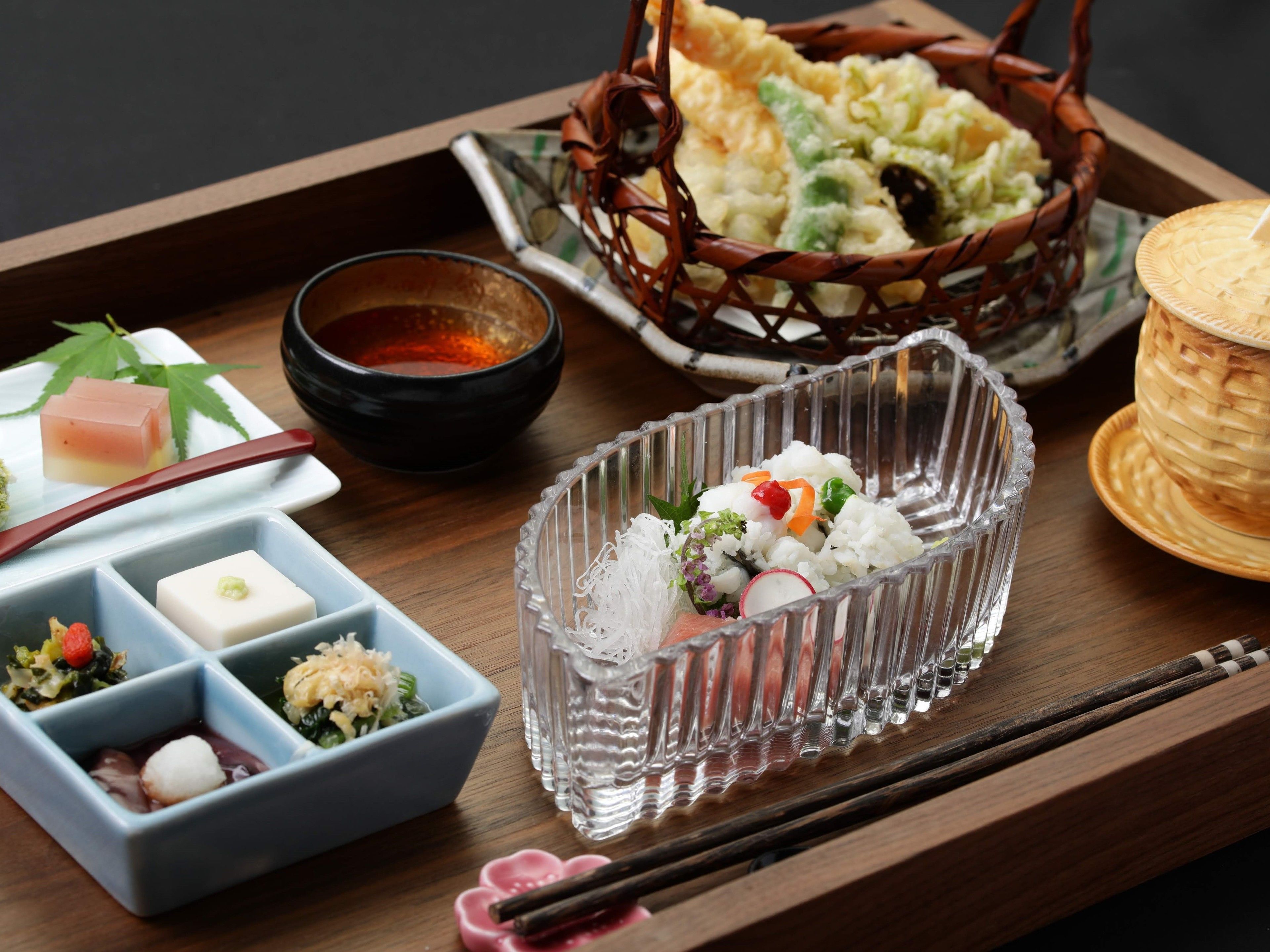 Un plateau contenant divers plats japonais, notamment des sushis, des légumes marinés et un petit bol de soupe.