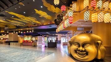 A spacious indoor area with a large golden statue, ceiling decorations, and various shops.
