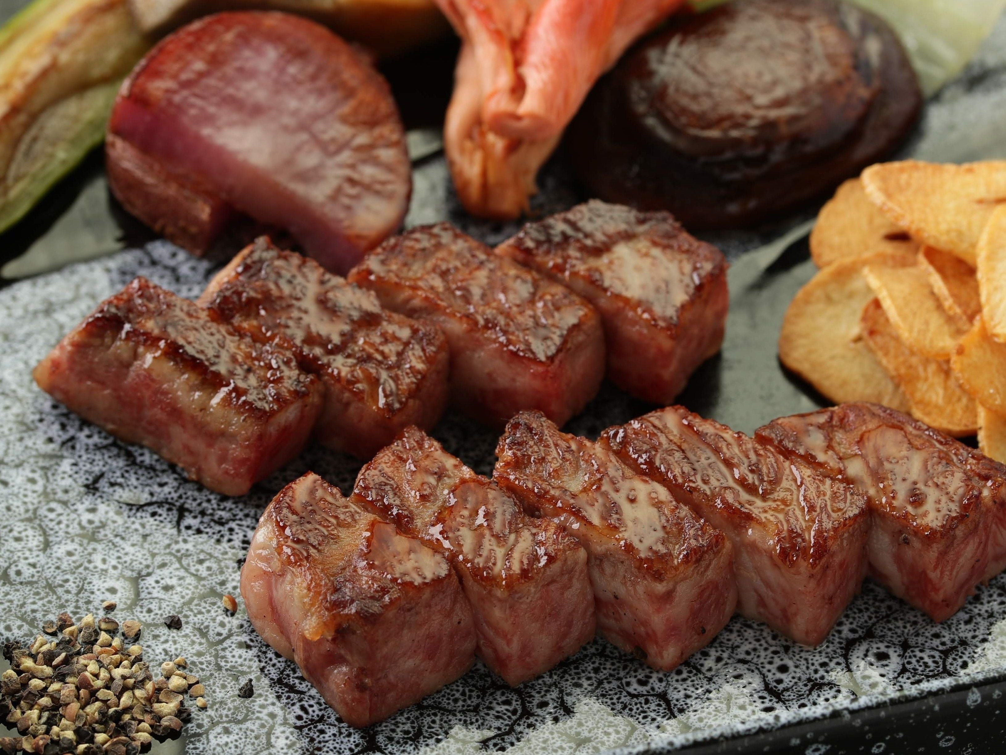 Ein Teller mit geschnittenem Fleisch, Gemüse und Pommes.