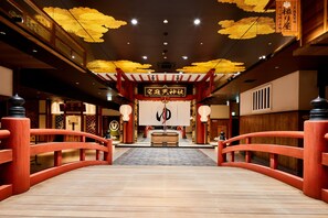 A traditional Japanese interior with a wooden bridge leading to a central altar.