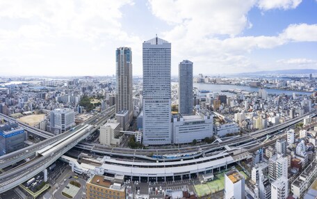A high-rise urban area with modern architecture, including a prominent building with a unique design and a circular structure with a roof.