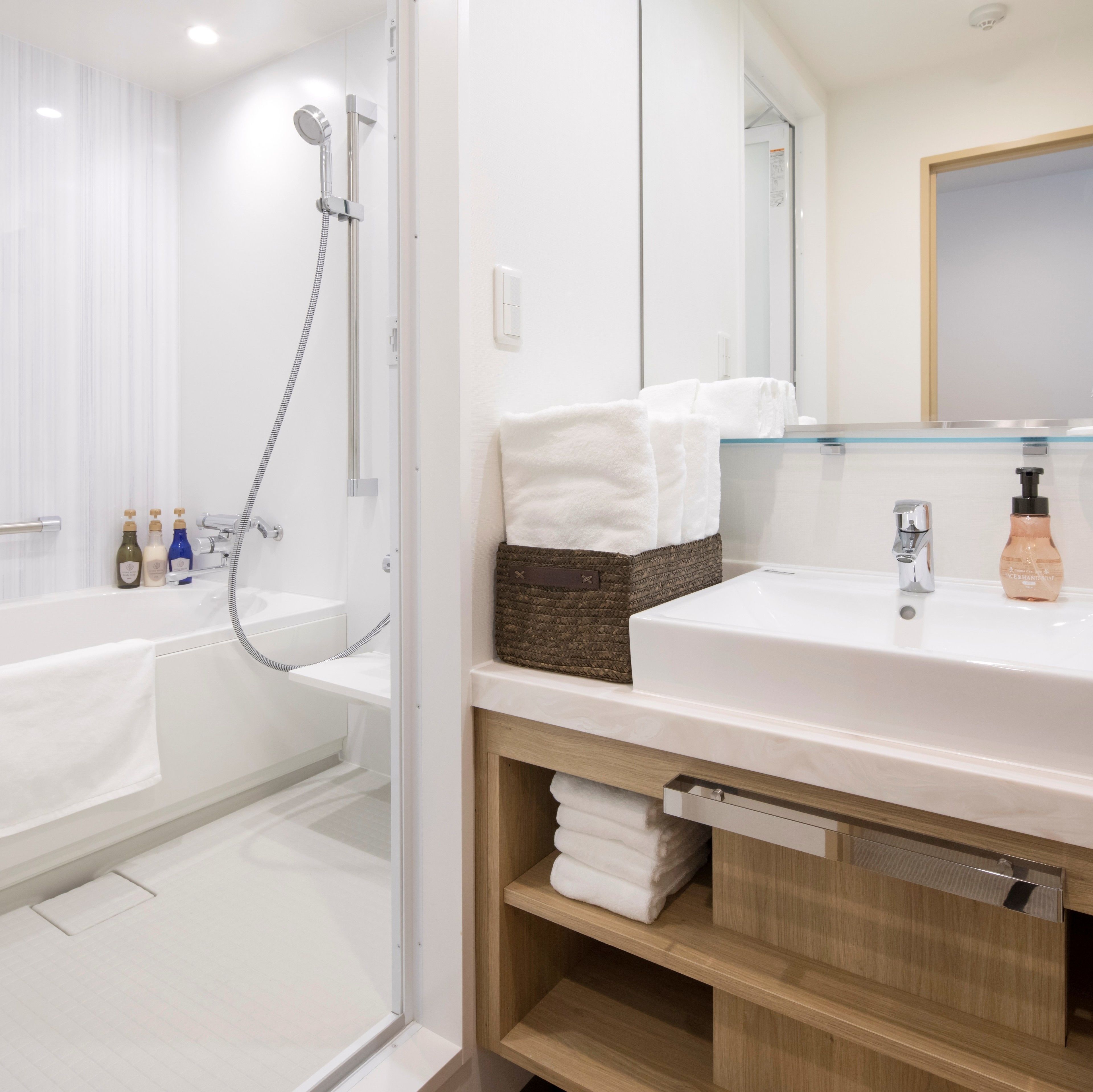Une salle de bain moderne avec une douche à l’italienne en verre, un lavabo blanc et un meuble-vasque en bois.