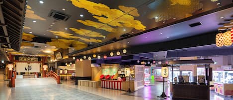Un espacio interior amplio con un diseño moderno en el techo, máquinas expendedoras y un puesto de comida tradicional.