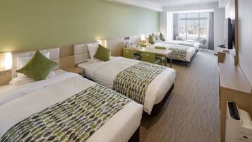 A hotel room with three beds, a desk, and a television.