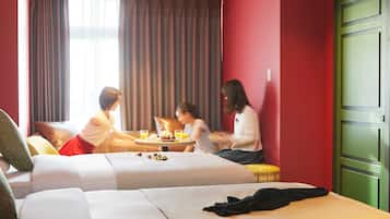 Une chambre d’hôtel avec deux lits, une table à manger avec des aliments pour le petit-déjeuner, et une porte verte.
