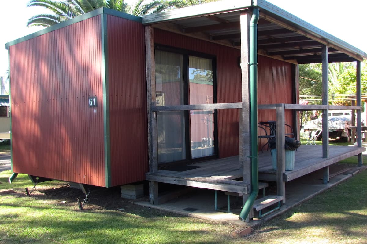 A small, single-story building with a porch, numbered 61, and a covered outdoor seating area.