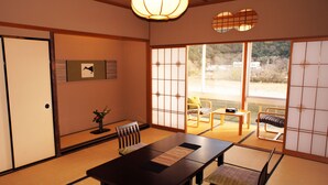 Habitació japonesa tradicional amb sòls de tatami, una taula baixa i portes corredisses que donen a un balcó.