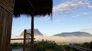 Eine Bambuskonstruktion mit einem Reetdach mit Blick auf eine gebirgige Landschaft.