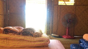 Ein Zimmer mit einem Bett, einem Ventilator und einem Fenster.