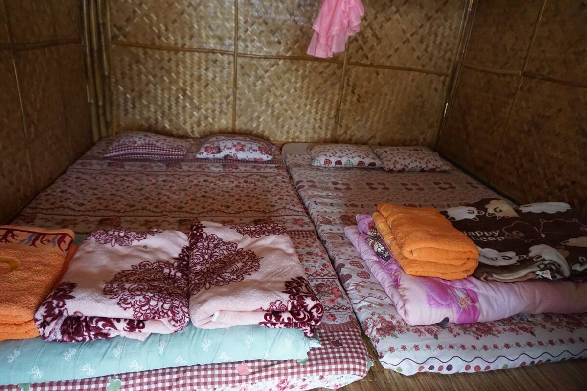 Una habitación con una cama cubierta con ropa de cama estampada, una manta doblada y una almohada.