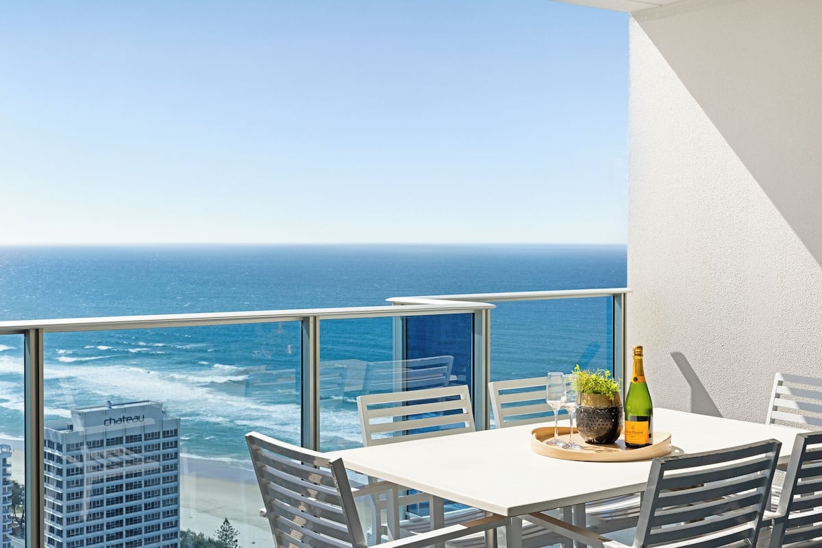 A balcony with a table, chairs, a bottle of champagne, and a potted plant.