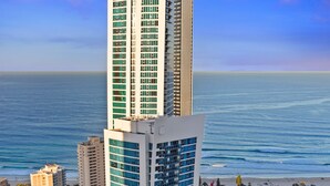 A high-rise hotel with a modern design, located near a beach with a view of the ocean.