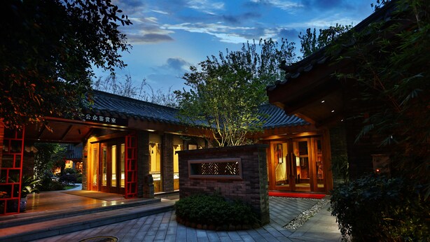 A traditional building with a tiled entrance, a stone pillar, and a red gate. - HuanHuaHongTai hotel (Chengdu)