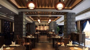 A restaurant with wooden tables and chairs, stone pillars, and hanging pendant lights. - HuanHuaHongTai hotel (Chengdu)