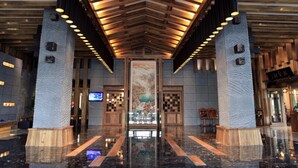 A lobby with a high ceiling, wooden beams, and a large central artwork. - HuanHuaHongTai hotel (Chengdu)