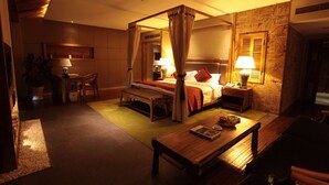 A four-poster bed with a canopy, a bedside table with a lamp, a wooden bench, and a small table with a bowl. - HuanHuaHongTai hotel (Chengdu)