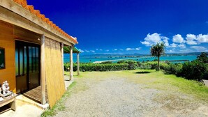 A wooden building with a view of a turquoise sea and a clear sky. - Churahashi (Nakijin)