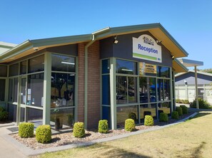 A reception area with a clear sign, glass doors, and a brick wall. - Tasman Holiday Parks - Easts Beach (Kiama)