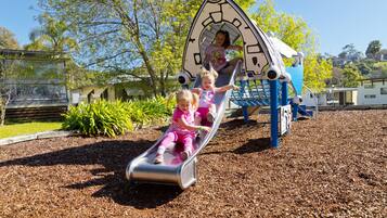 A playground with a slide and climbing structures.
