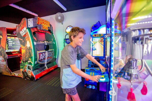 A child playing a video game in an arcade with various machines.