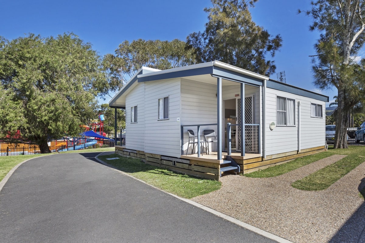 A single-story mobile home with a covered porch and a small patio area.