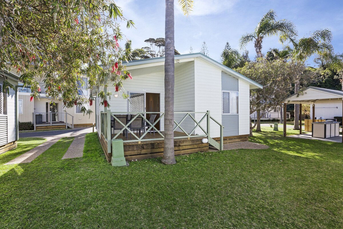 A single-story mobile home with a fenced porch, a small deck, and a well-maintained lawn.