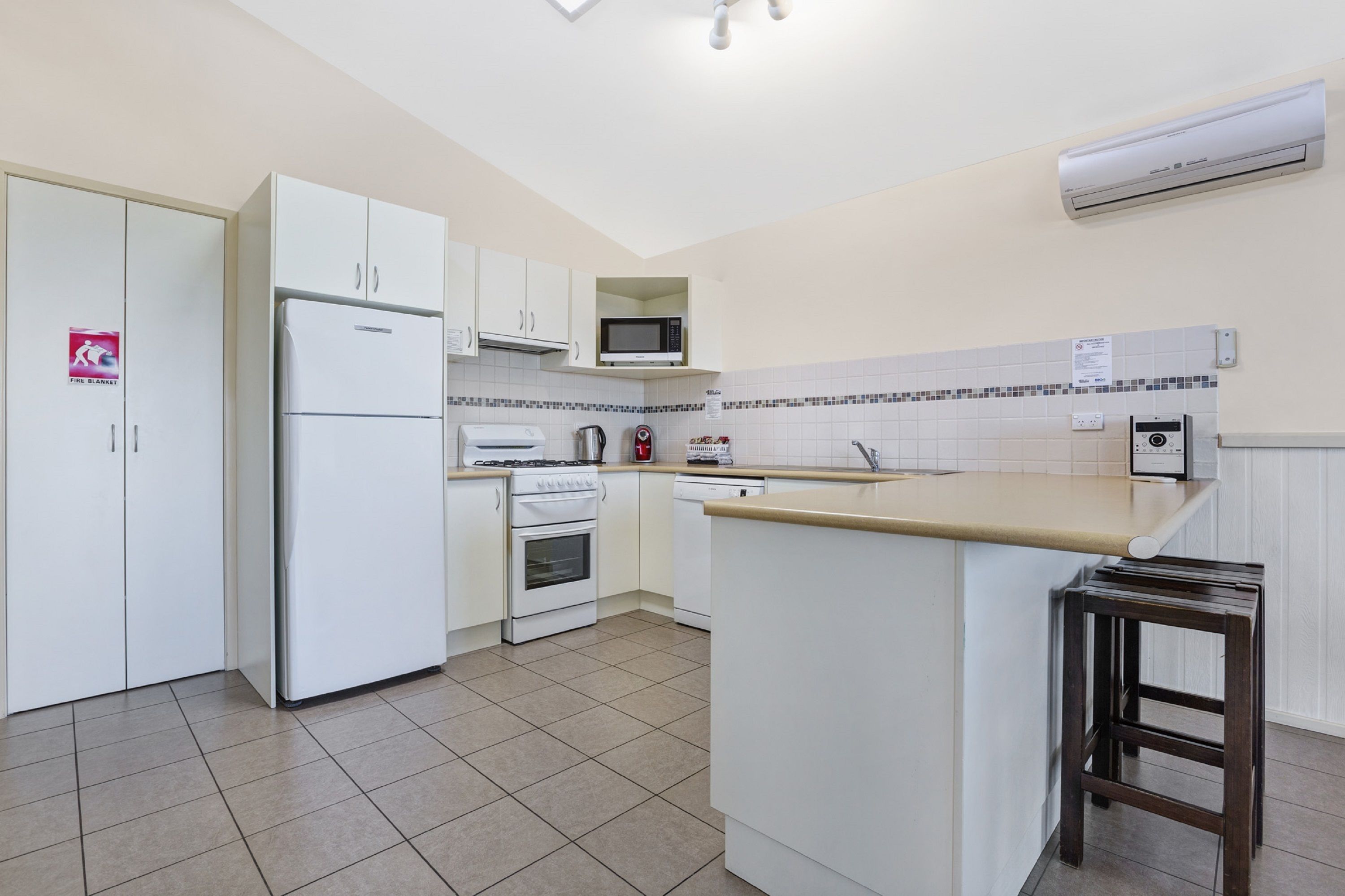 A compact kitchen with white cabinets, a microwave, a stove, and a sink.