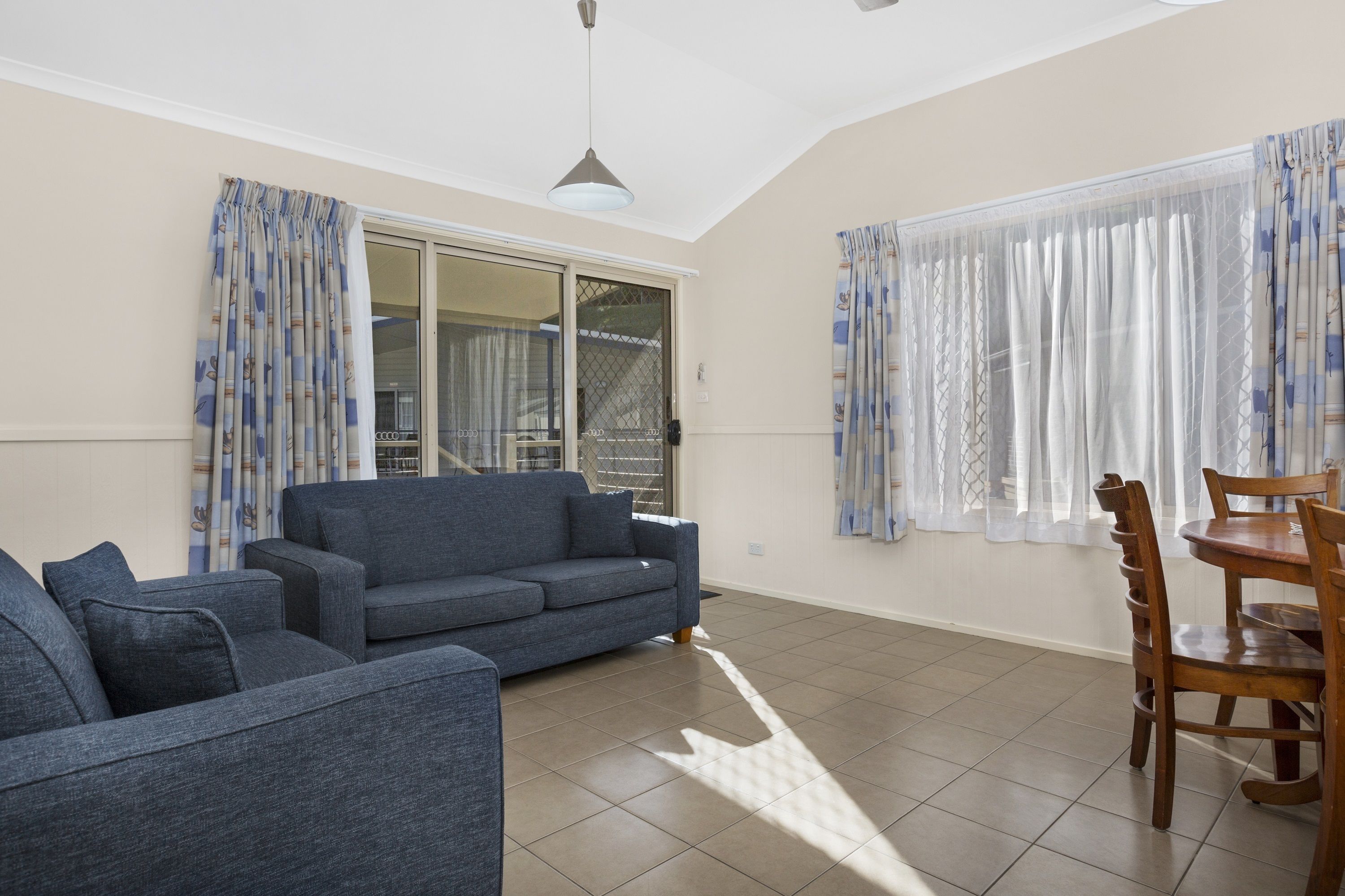 Ein Wohnzimmer mit einer Couch, einem Esstisch mit Stühlen und einer Schiebetür, die auf einen Balkon führt.