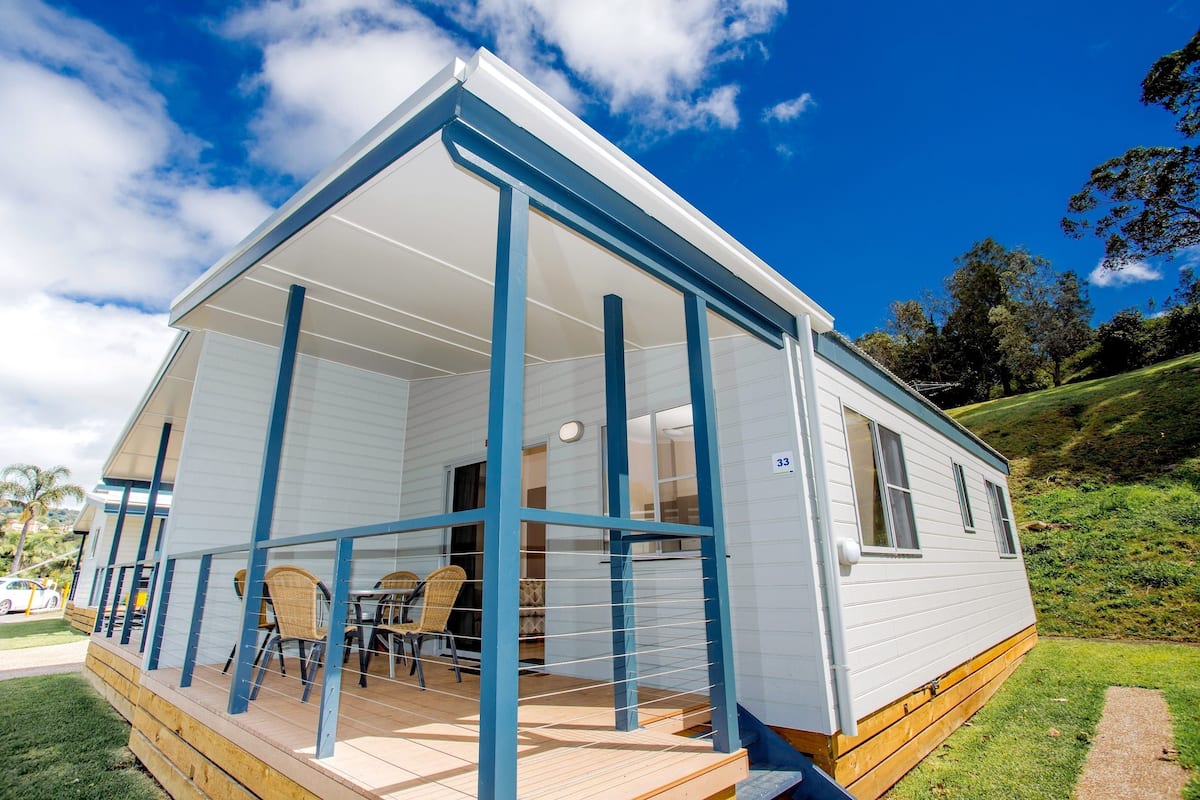 A mobile home with a porch, outdoor seating, and a number '33' sign.