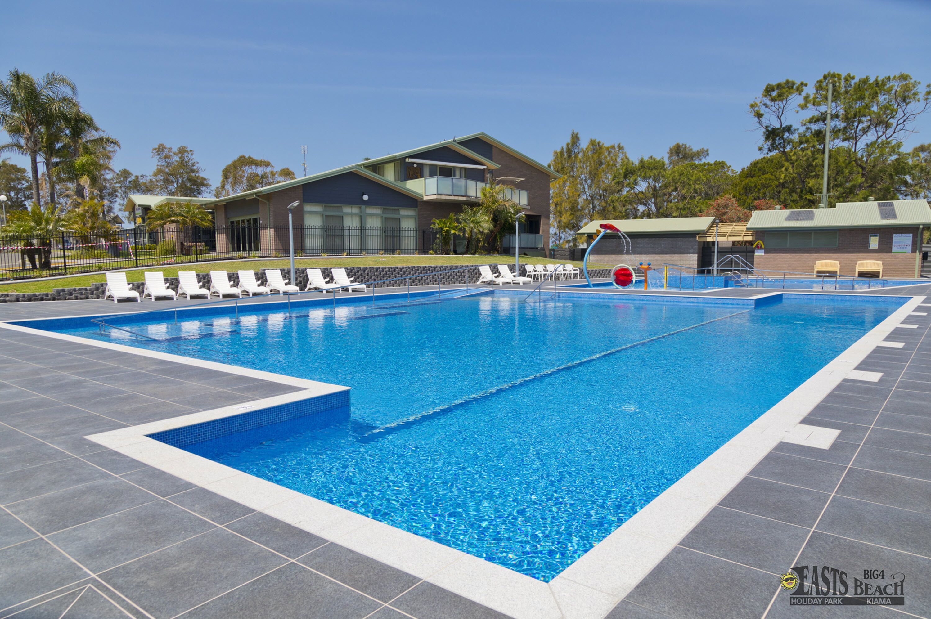 A swimming pool with lounge chairs and a building in the background.