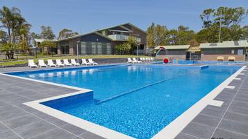 A swimming pool with lounge chairs and a building in the background.