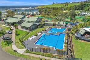A resort with two swimming pools, a parking area, and a view of the ocean. - Tasman Holiday Parks - Easts Beach (Kiama)