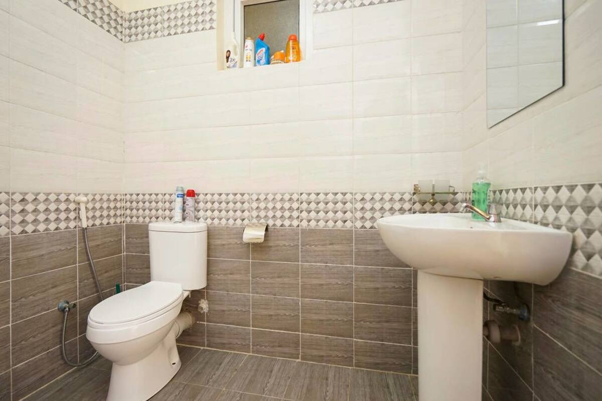 A bathroom with a toilet, sink, and tiled walls.
