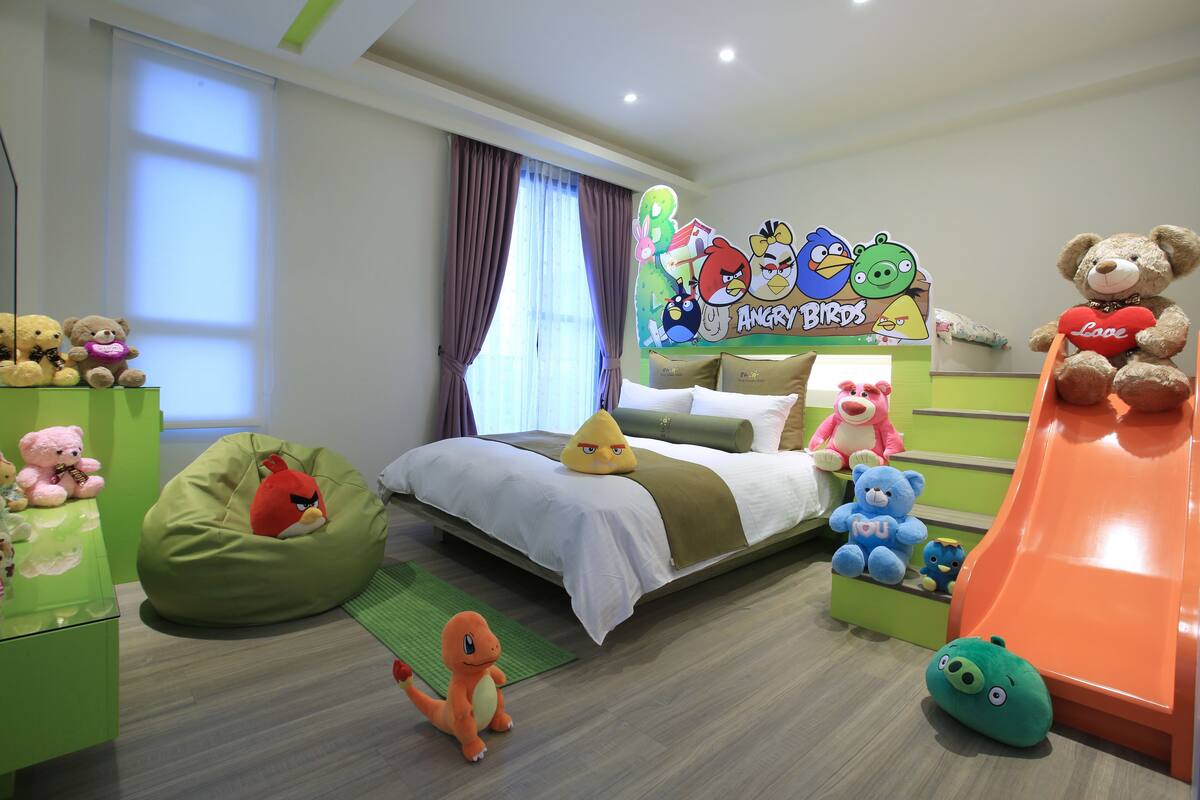 Una habitación infantil con cama, puf, juguetes y un tobogán.