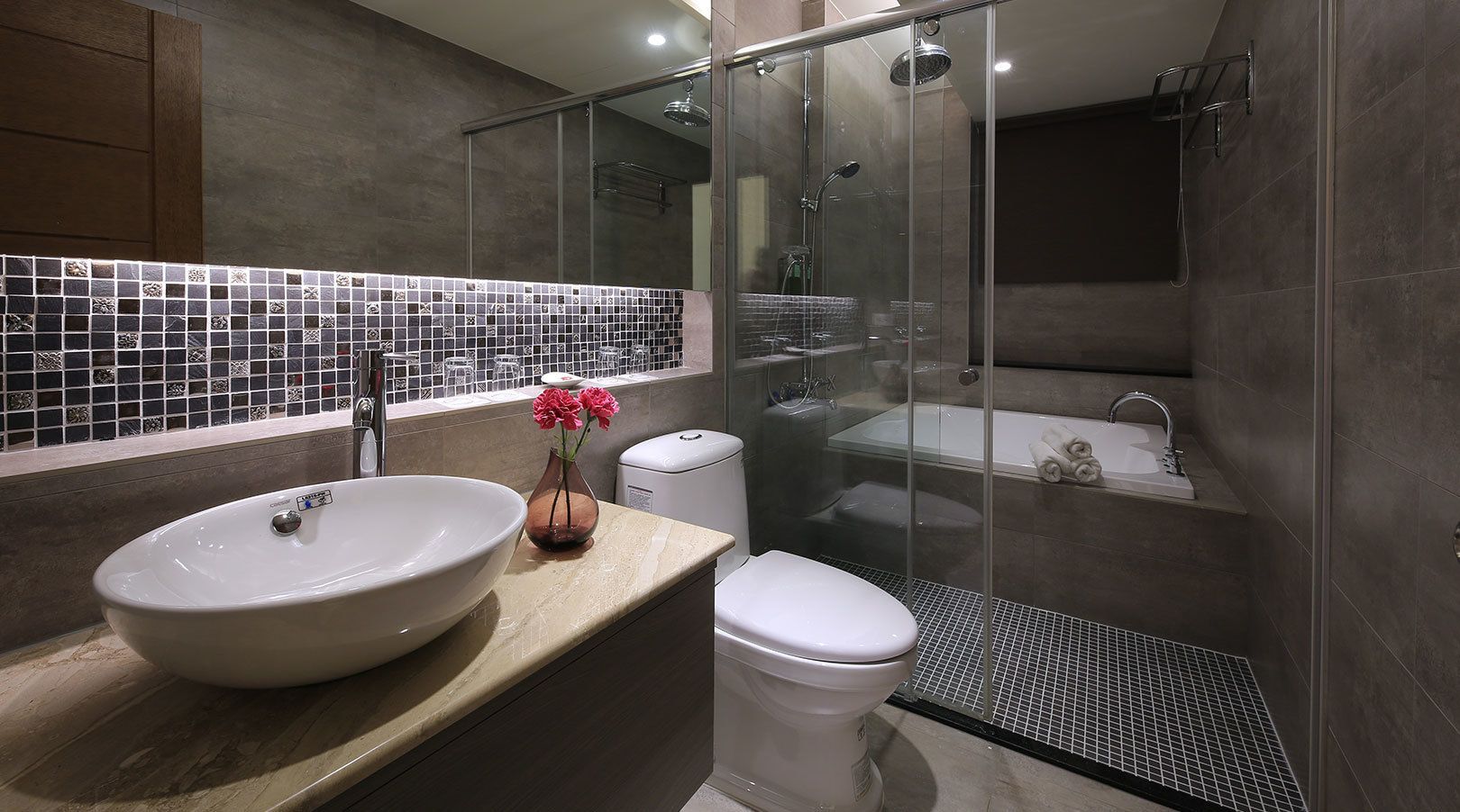 Un baño moderno con un lavamanos amplio, inodoro y ducha con mampara de vidrio.