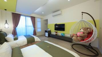 A hotel room with two beds, a hanging chair with a teddy bear, a TV on the wall, and a window with curtains.