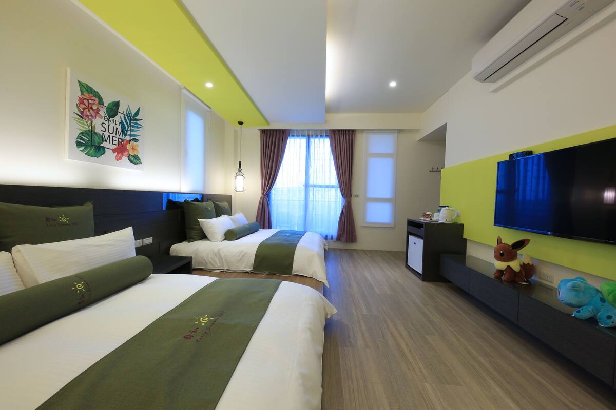 Habitación de hotel con dos camas, televisor, un escritorio pequeño y ventana con cortinas.