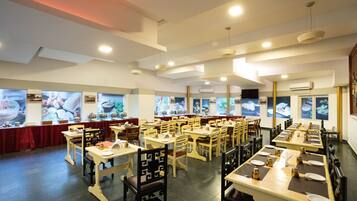 A restaurant with multiple dining tables and chairs, arranged in rows.