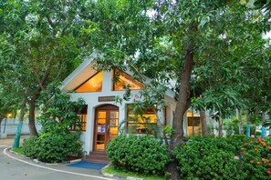 A reception area with a sign, surrounded by lush greenery and trees. - Shelter Beach Resort (Tirupporur)