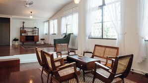 A spacious room with a wooden dining table and chairs, a green armchair, and a bookshelf.