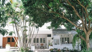 A house with a garden, a dining area, and a kitchen visible through the windows.