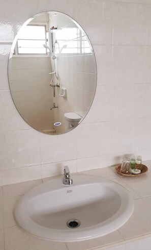 A bathroom with a round mirror, a sink, and a toilet.
