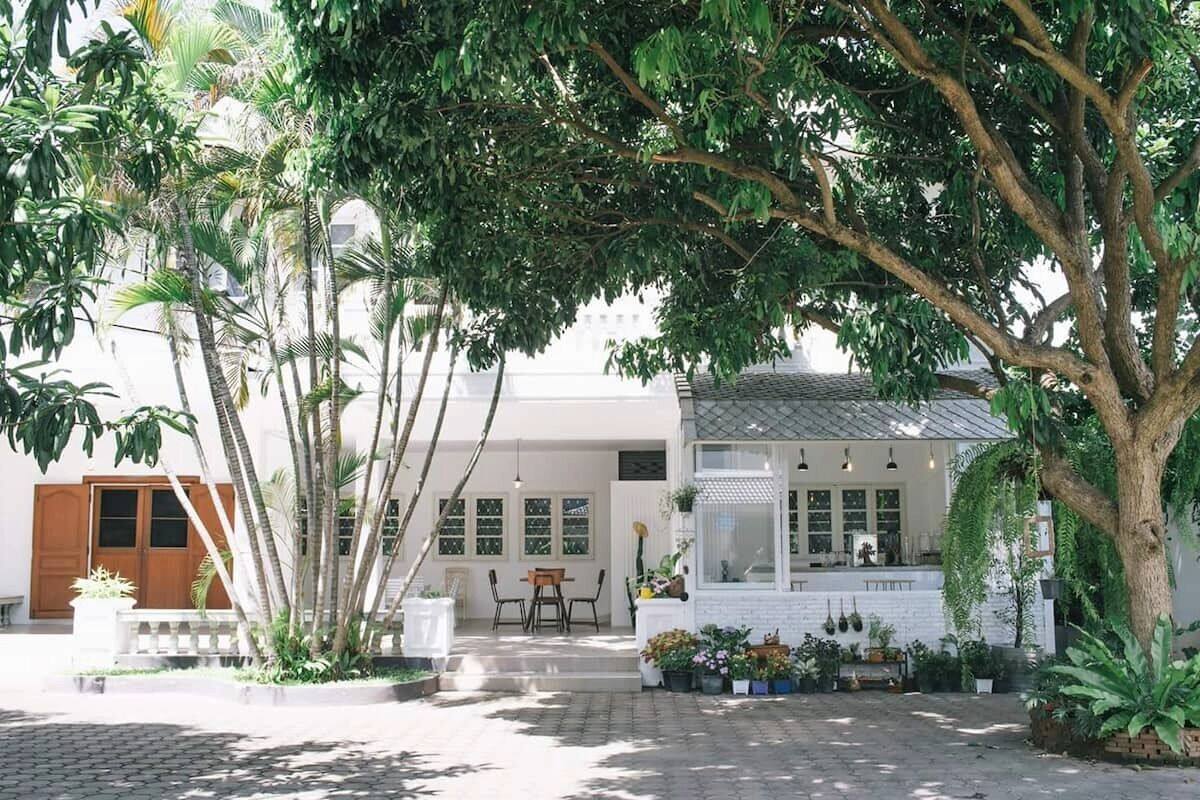 A courtyard with a white building, a wooden door, and a dining area.