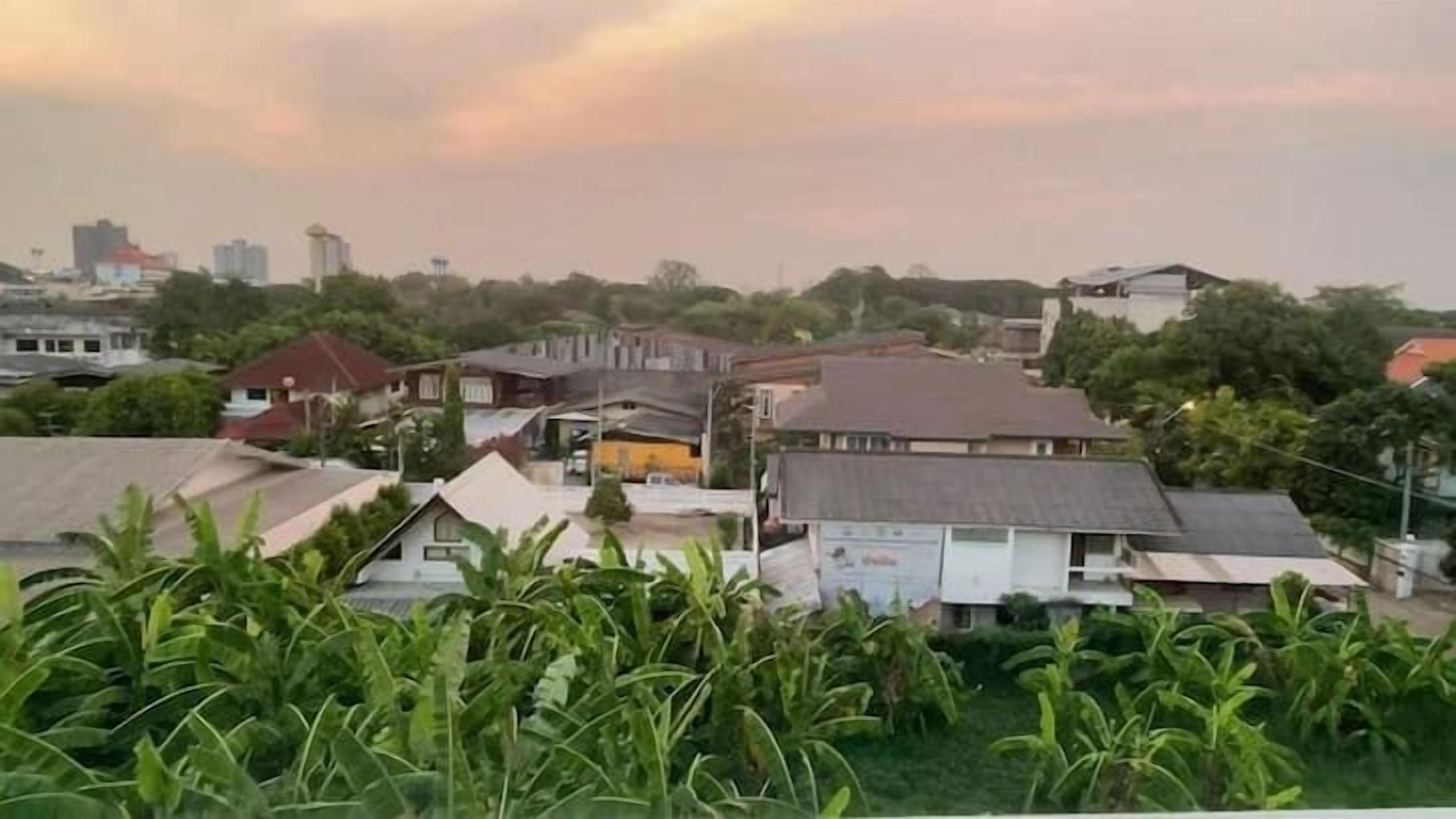 A residential area with houses, some greenery, and a distant city skyline.