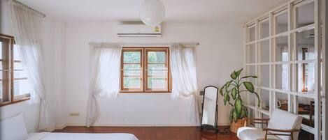 Una habitación con una cama, una silla, una planta en maceta, un espejo y un armario.