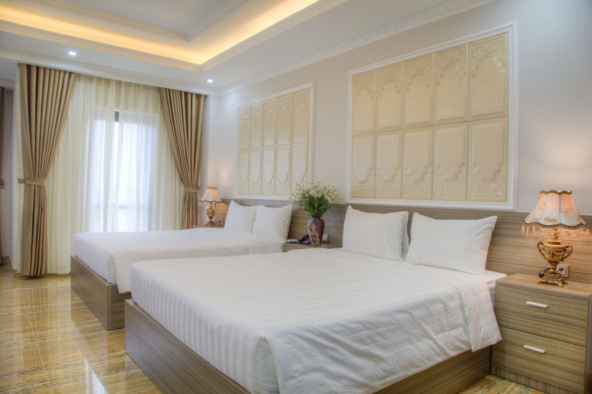 A hotel room with two beds, a nightstand, a lamp, and a decorative wall panel.